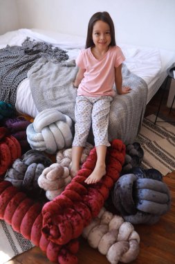 Çocuk kız pijama alışılmadık yastıklar arasında oynuyor.