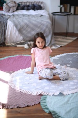 Çocuk kız yuvarlak mat katta oturur .