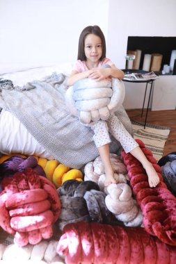 Çocuk kız pijama alışılmadık yastıklar arasında oynuyor.