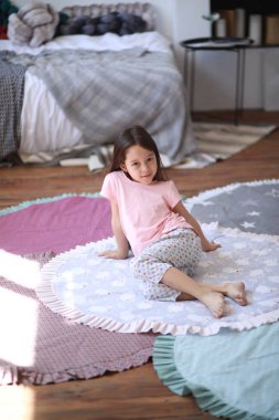 Çocuk kız yuvarlak mat katta oturur .