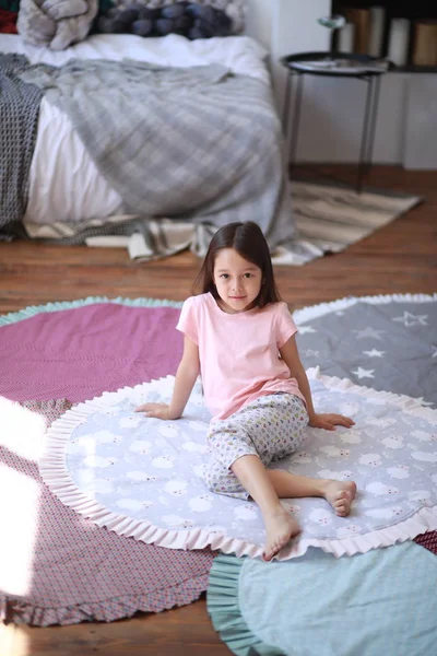Niña niña se sienta en el suelo en la alfombra redonda  . — Foto de Stock