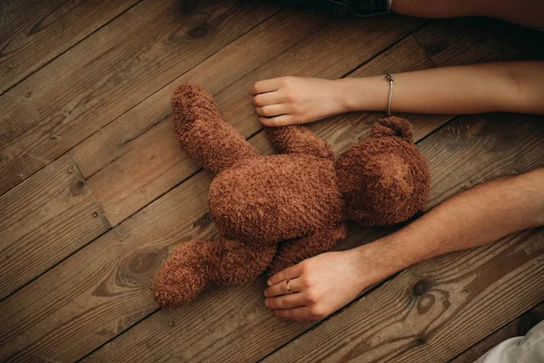 Male and female hands hold a teddy bear. — Stock Photo, Image