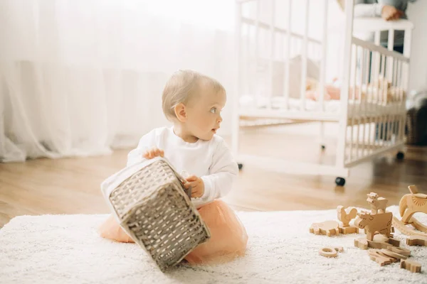 Niña se sienta en la alfombra y juega con la cesta . — Foto de Stock