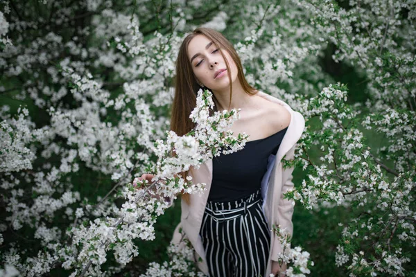 Une jeune femme se relaxe parmi les cerisiers en fleurs . — Photo