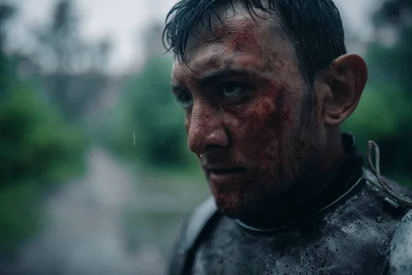 Portrait of young man in the image of a medieval knight with blood and wounds on his face. — Stock Photo, Image