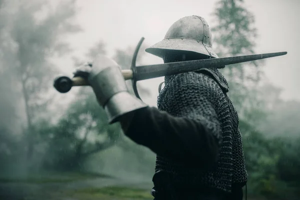 Medieval knight stands with his sword in the misty forest. — Stock Photo, Image