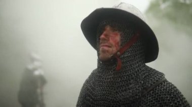 Yağmurda puslu ormanın arka planda yüzünde kan ve yaralar ile zırh ortaçağ şövalyesi portresi.