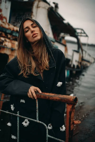在一艘废弃的旧船的背景下摆姿势的年轻女子 — 图库照片