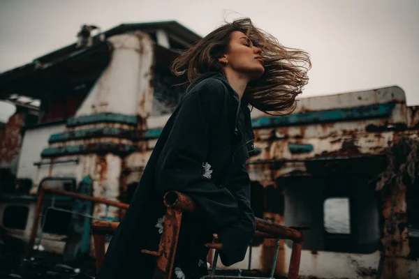 Jonge vrouw poseren tegen de achtergrond van een oud verlaten schip — Stockfoto