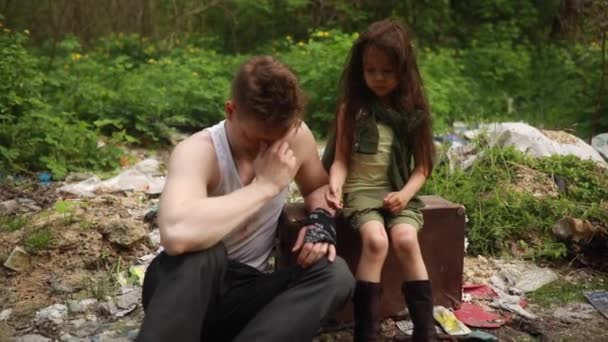 一个无家可归的父亲和女儿坐在垃圾堆上 绝望和悲伤 眼里含着泪水 贫穷和无家可归的概念 — 图库视频影像