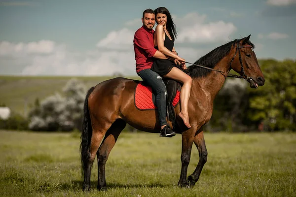 Young couple is riding a brown horse. — Stock Photo, Image