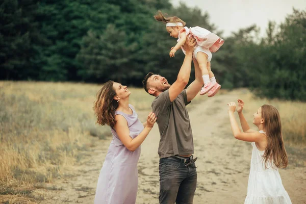 Glückliche Familie hat Spaß beim Spaziergang und wirft ihre Tochter hin. — Stockfoto