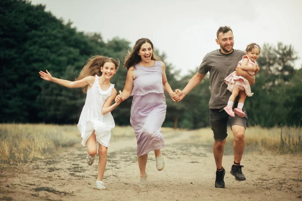 Familia feliz se divierte, corre y ríe en un paseo . — Foto de Stock