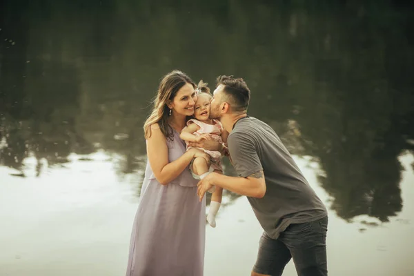 Šťastná rodina se směje vedle jezera. — Stock fotografie