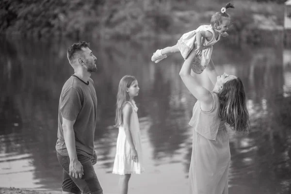 Glückliche Familie hat Spaß beim Spaziergang und wirft ihre kleine Tochter hoch — Stockfoto