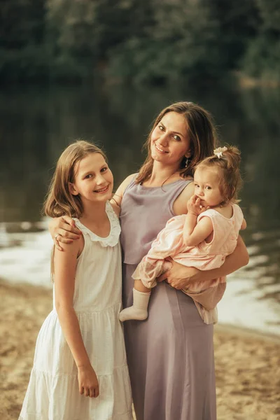 Mother with her two daughters is next to the lake. — Stock Photo, Image