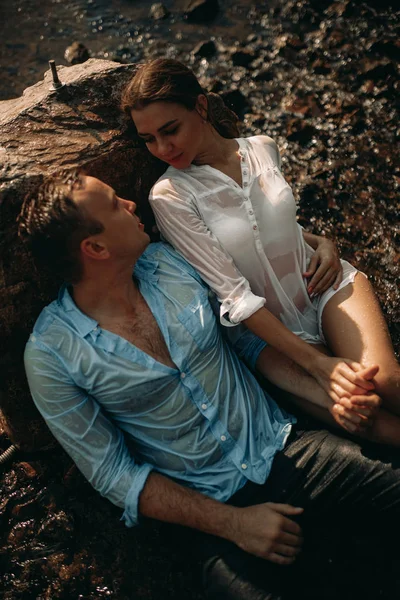 Una pareja sentada junto a la roca y cogida de la mano . — Foto de Stock