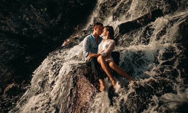 Couple étreignant sous les ruisseaux d'une cascade . — Photo
