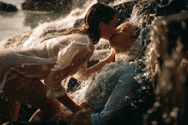 Een paar tijdens het vrijen naast een waterval. — Stockfoto