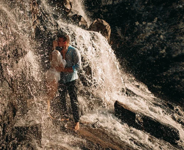 Paar zoenen onder de stromen van een waterval. — Stockfoto