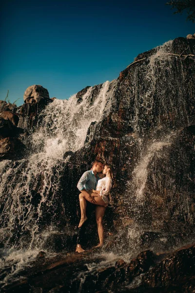 Pár objetí na pozadí vodopádu a nebe. — Stock fotografie