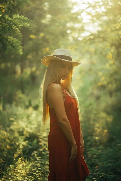 Una giovane donna è in piedi nella foresta illuminata dal sole . — Foto Stock