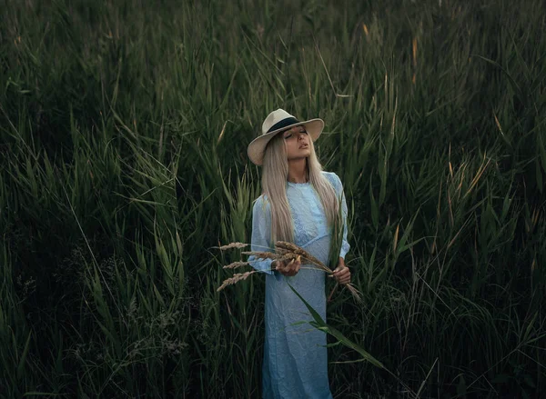 Jeune femme se tient sur la prairie parmi la canne . — Photo