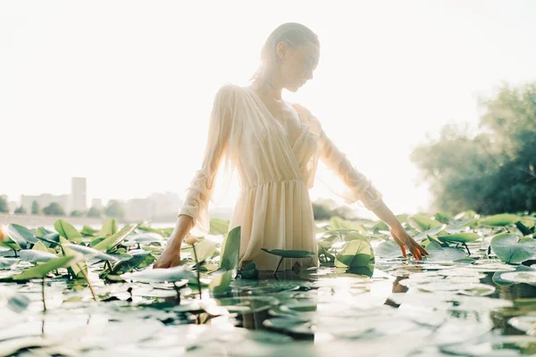 Giovane donna in piedi in acqua tra la giglio gialla . — Foto Stock