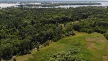 Yol ve orman ile glade üzerinde drone tarafından havadan anket. Mesafe nehir, köprü ve şehir görülebilir.