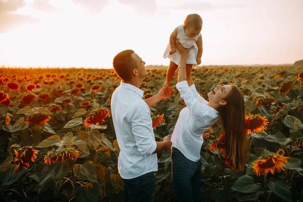 Happy family with baby has a fun and plays in the sunflower field. — Stock Photo, Image