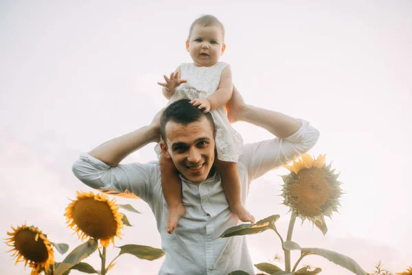 Pai feliz com sua filhinha está no campo de girassol . — Fotografia de Stock