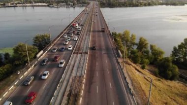 Uzak şehir manzaralı bir nehir üzerinde bir köprü üzerinde yoğun trafiğe drone görünümü. 