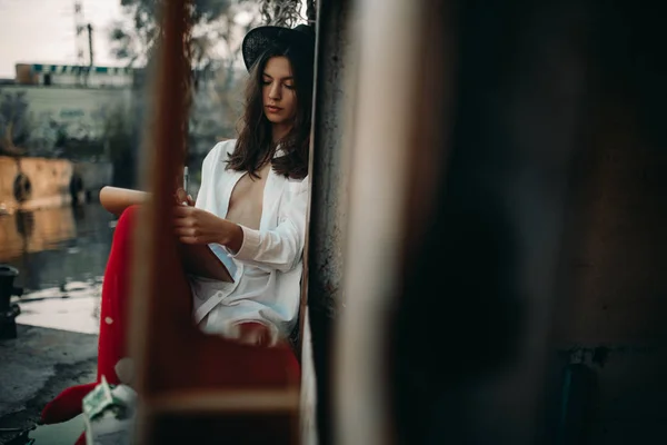 Mladá žena sedí a kreslí na starou opuštěnou loď. — Stock fotografie