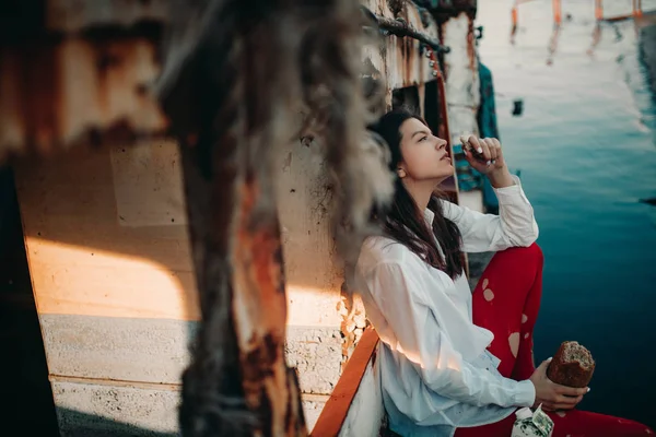 오래된 버려진 배에서 빵을 먹고 있는 한 젊은 여성. — 스톡 사진