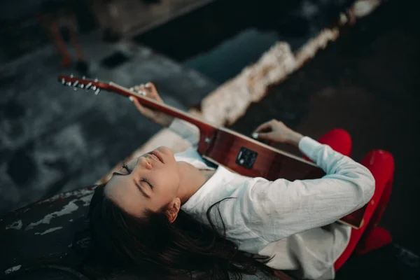 Молода жінка лежить і грає на гітарі на старому покинутому кораблі . — стокове фото