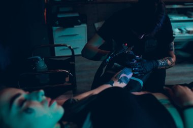 Dövme sanatçısı bir kızın kolunda bir dövme oluşturur.