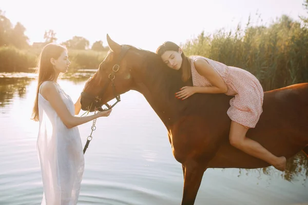 Женщина лежит верхом на лошади, а другая женщина стоит рядом . — стоковое фото