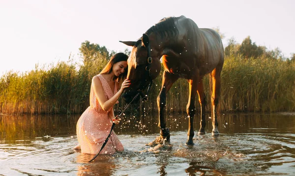 Mulher senta-se ao lado do cavalo que produz salpicos na água — Fotografia de Stock