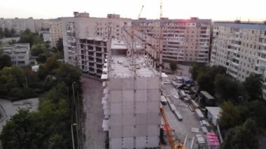 İnşaat sırasında çok katlı yüksek katlı binanın yanındaki şantiyeye drone'dan görünüm.