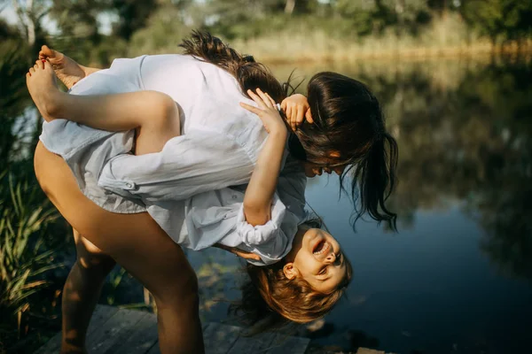 Anne ve kızı oynamak ve küçük bir nehir yakınında eğlenmek. — Stok fotoğraf