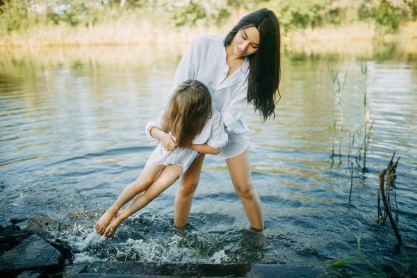 Moeder en dochter spelen en plezier hebben in het water op een rivier. — Stockfoto