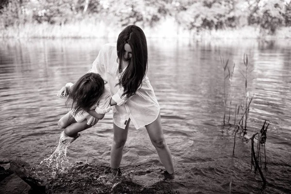 Mãe e filha brincam e se divertem na água em um rio . — Fotografia de Stock