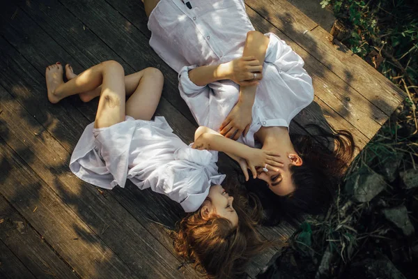 Mother and daughter lying on old bench in the forest during the — Stock Photo, Image