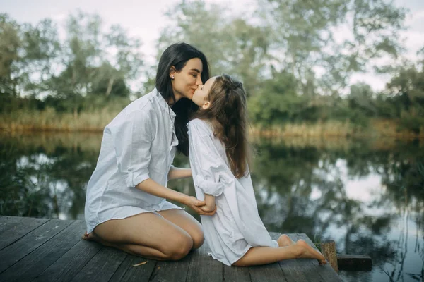 Matka i córka pocałunek i bawić się w pobliżu małej rzeki. — Zdjęcie stockowe