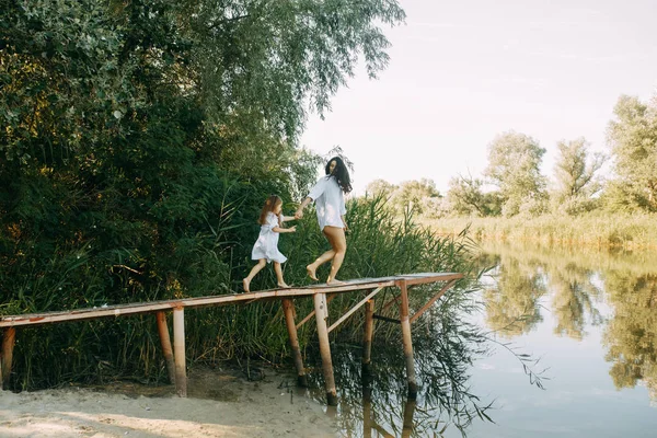 Mutter und Tochter rennen und amüsieren sich auf einer Holzbrücke — Stockfoto
