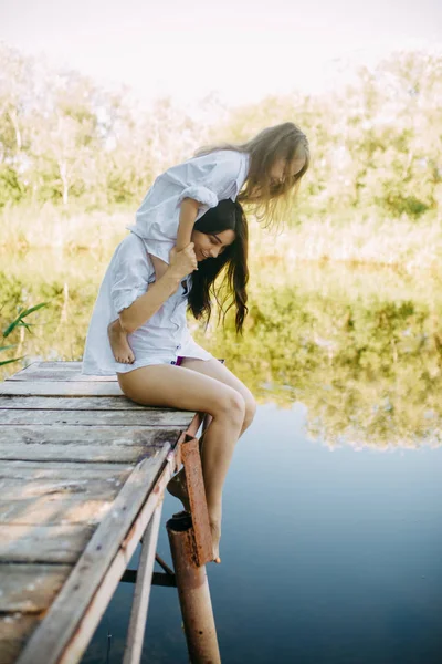 Mère et fille s'amusent sur un pont en bois près de la rivière . — Photo