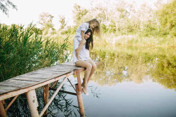 Mère et fille s'amusent sur un pont en bois près de la rivière . — Photo