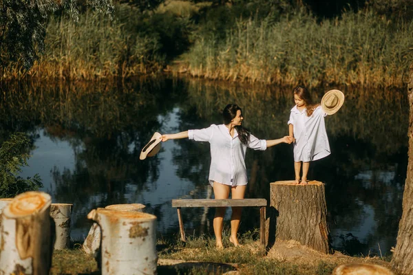 Mutter und Tochter spielen neben Stümpfen auf Flusshintergrund — Stockfoto