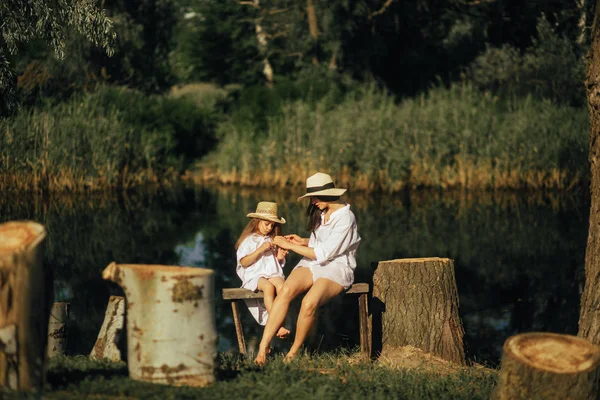 Mutter und Tochter sitzen auf Bank neben Stümpfen im Hintergrund — Stockfoto
