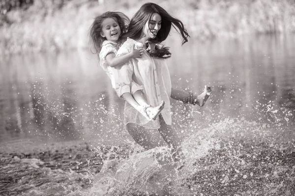 Mother and daughter run and have fun in the water with many spla